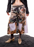 Person wearing a long camouflage skirt with a belt on a black surface.
